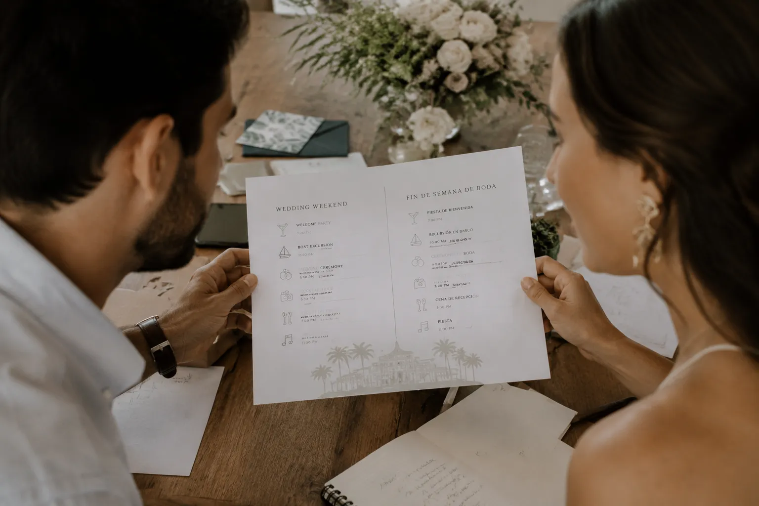 Couple reviewing a bilingual wedding weekend itinerary with English and Spanish schedule sections